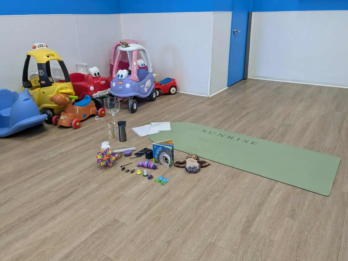 Tapis de yoga entouré de petits instruments, de livres et de jouets pour une séance avec des enfants