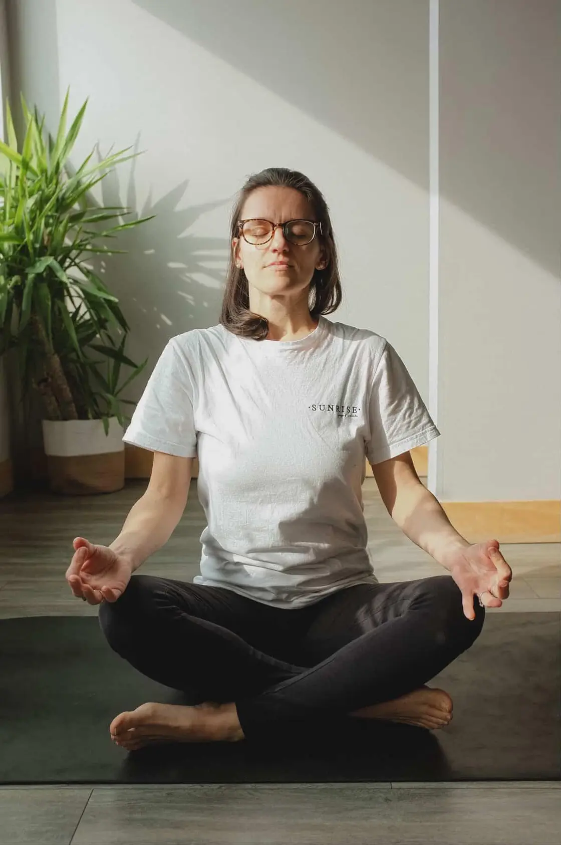 Jessica en méditation assise, les yeux fermés, dans un studio baigné de lumière